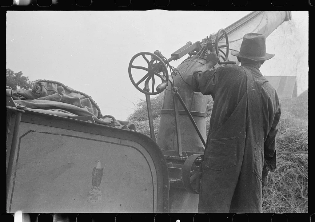 Adjusting straw stocker on grain separator, central Ohio, 1938