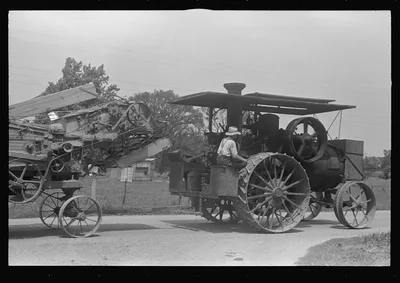 Steam tractor pulling grain separator along country road, central Ohio, 1938